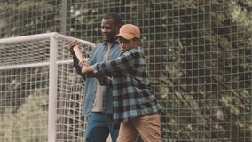Tilt up slowmo of African American man showing how to bat in baseball while practicing together outdoors on grass in park - Powered by Shutterstock - Get 15% off with code: PIKWIZARD15