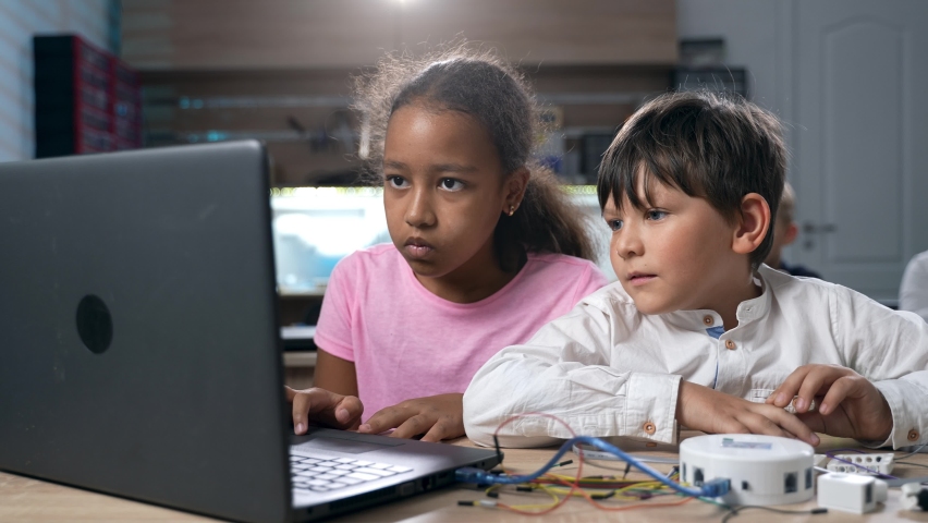Multiethnic elementary school kids building robots developing program for software robotics engineering using laptop at classroom lab. AI technologies development. STEM education concept. 4k footage - Powered by Shutterstock - Get 15% off with code: PIKWIZARD15