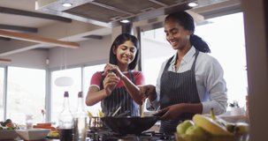 Video of happy diverse female friends preparing meal. Friendship, spending quality time together at home.