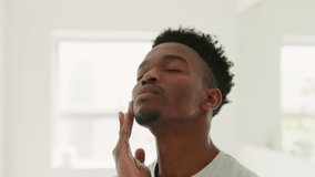 Skincare, mirror and beauty with black man in bathroom for cosmetics, facial or dermatology with morning routine. Cleaning, wellness or grooming with young guy and face cream, lotion or moisturizer - Powered by Shutterstock - Get 15% off with code: PIKWIZARD15
