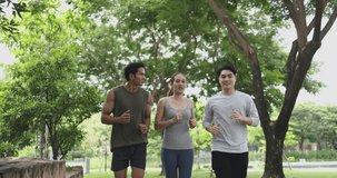4K video Slow motion Asian young man and woman jogging together in green park. Concept for healthy lifestyle and outdoor life.