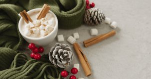 Video of cup of hot chocolate with marshmallows and warm blanket over grey background. Christmas, tradition and celebration concept.