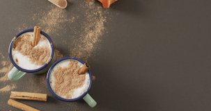 Video of cups of hot chocolate with cinnamon over grey background. Christmas, tradition and celebration concept.