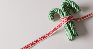 Video of green christmas canes with ribbon over white background. Christmas, tradition and celebration concept.