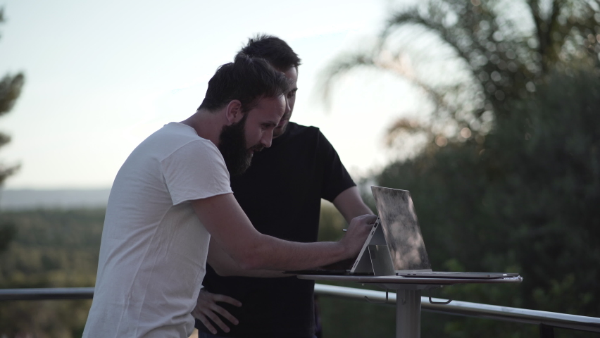 two business people consulting on a project looking at computer monitor screen outside