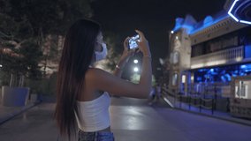 Side view of Asian girl take video of the House of Horrors at the fair 