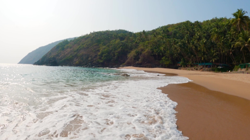 4K Wide angle shot of sea waves on the shore of a tropical beach at Kakolem beach in South Goa, India. Sea waves on the shore of a tropical beach island. Sea waves at the beach on a remote island.  | Shutterstock HD Video #1094553025