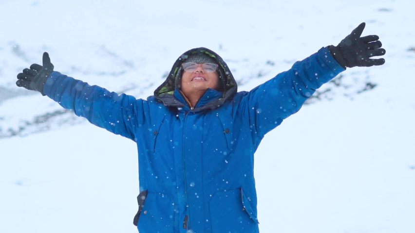 Portrait of Indian female traveler open her arms and enjoying snowfall on snow covered mountain during winter at Manali, Himachal Pradesh, India. Slow motion shot of young woman enjoying snowfall.  | Shutterstock HD Video #1094553171