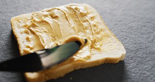 Video of close up of toast with peanut butter on gray background. Food, party and copy space concept.