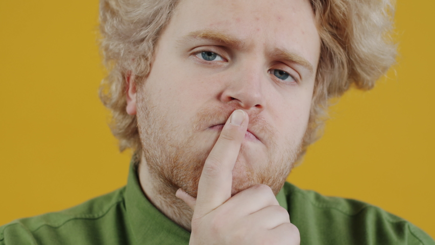 Close-up portrait of serious and worried guy thinking rubbing chin contemplating on problem on yellow background. People and emotions concept. | Shutterstock HD Video #1094561141