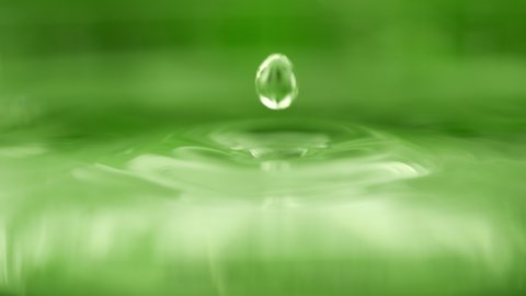 Drop is falling into green liquid. Crystal clear water splash. Concept of natural springs and wellness or beauty products. Green tea or aloe vera extract. Natural mineral water in slow motion 库存视频