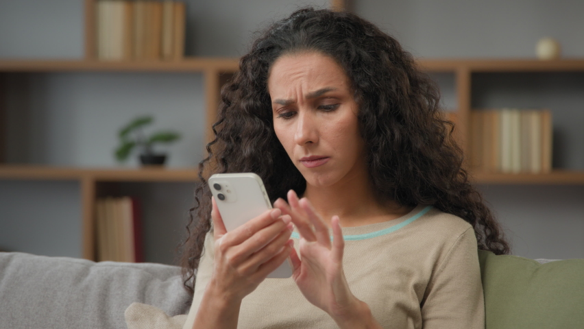 Closeup angry confused puzzled stressed nervous adult woman looking at cellphone screen at home has trouble with wifi connection feeling frustrated of receiving message or email with bad news chatting | Shutterstock HD Video #1094566575