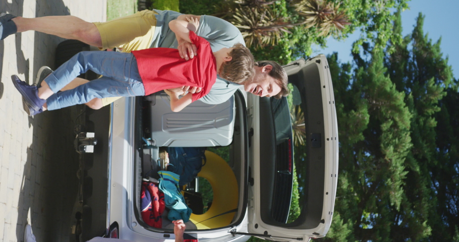 Vertical video of happy caucasian parents, father lifting son by open boot of packed car. family holiday, enjoying quality free time together. Royalty-Free Stock Footage #1094567387