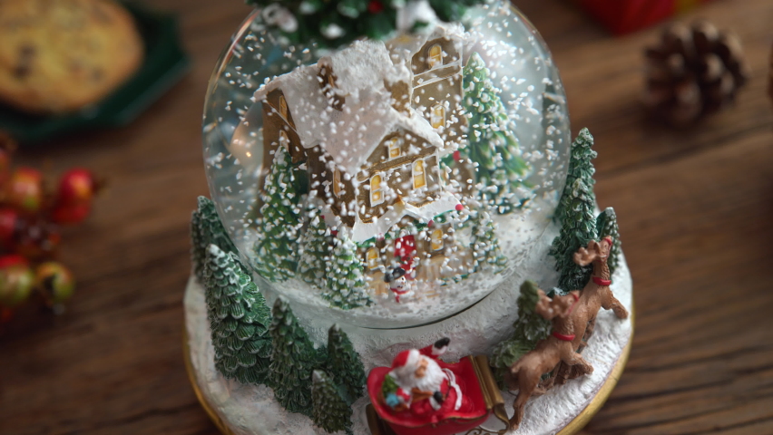 Snow Globe on Christmas Table with Snow Falling Inside and Shining Fire in the Background - Dolly in, Slow Motion Royalty-Free Stock Footage #1094568523