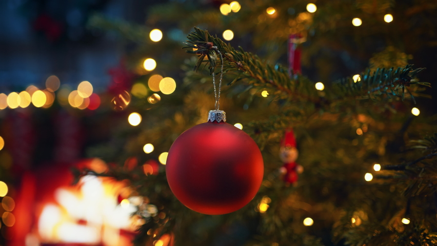 Christmas Tree Decorated with Red Glass Bauble and LED Lights with Blurred Burning Fireplace in the Background Royalty-Free Stock Footage #1094568527