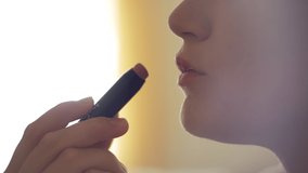 Close-up of a girl painting her lips. A woman holds lipstick in her hands. Make-up at home in front of the mirror. Preparation for the party and date. High quality 4k footage