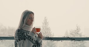 Woman drinks tea, and relax on terrace at home in winter day. Health care, authenticity, sense of balance and calmness. It's Snow time. 4K Video