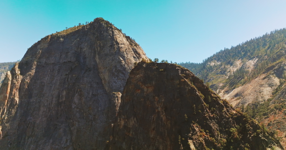 Enormous cliffs at the backdrop of blue clear sky. Yosemite National Park, California, United States on sunny daytime.