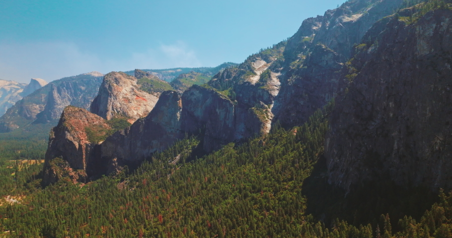 Beautiful rock formations in the United States National Park of Yosemite. Pine tree forest overgrowing the mountains. Sunny day clear sky backdrop.