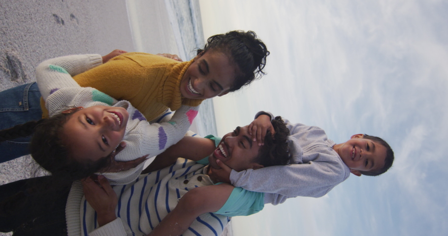 Vertical video of happy biracial family embracing on sunny beach. healthy, active time beach holiday. Royalty-Free Stock Footage #1094573273