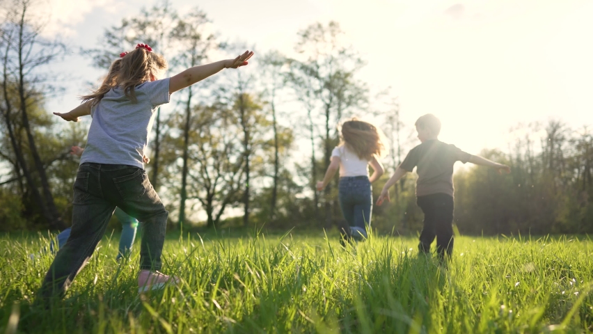 Children play in spring vacation park.Active happy group of kid run with a dog on grass in field in summer.Family in nature with pet.Child on play.Happy family concept.School in garden with dog | Shutterstock HD Video #1094574349
