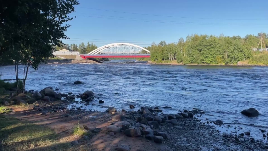 The big red bridge over the river, Wisconsin, a view from the shore on the water. a strong structure above a raging river with a strong current, cars move across the river