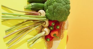 Vertical video of fresh vegetables with broccoli and peppers on yellow background. fresh and organic vegetable produce.