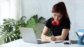 Asian teenage woman sitting in white office with laptop, she is a student studying online with laptop at home, university student studying online, online web education concept.