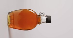 Vertical video of maple syrup in glass on white surface. Food, meal, cuisine and cooking concept.