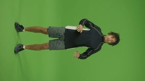 Vertical Footage. Motivated Sporty Mexican Man Doing Breathing Exercises Raising Legs Up and Down against Green Screen Background. Domestic Physical Jerks and Home Workout.