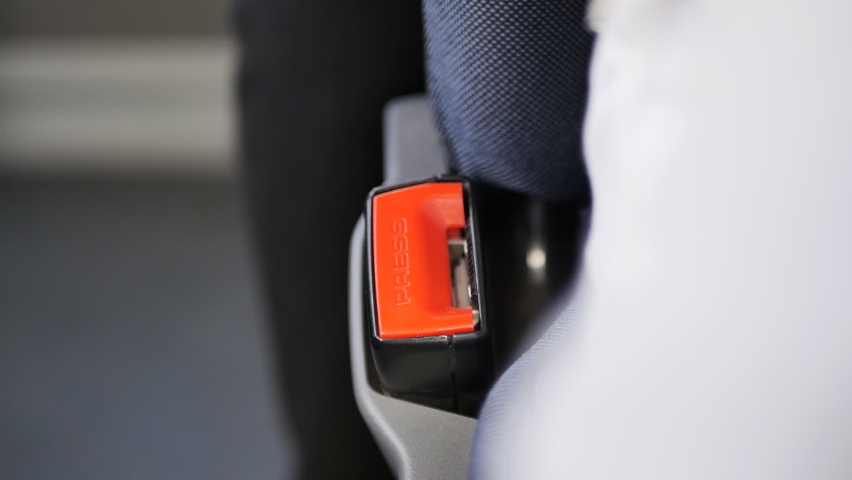 a man's hand fastens a seat belt while sitting in a car seat before starting to move. The bus passenger fastened the seat belt buckle. Driving safety. Close-up Royalty-Free Stock Footage #1094594225
