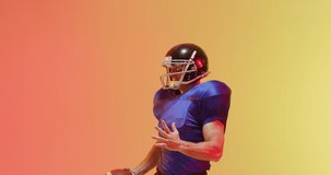 Video of close up of caucasian american football player in helmet with ball over orange background. American football, sports and competition concept.