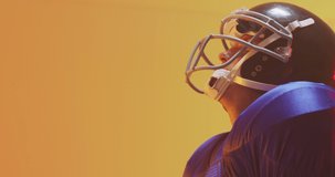 Video of close up of caucasian american football player in helmet with ball over orange background. American football, sports and competition concept.