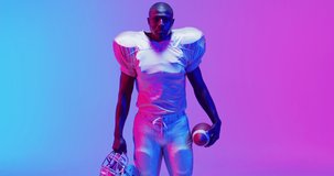 Video of diverse american football players over yellow to orange background. American football, sports and competition concept.