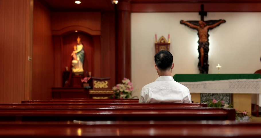 Asian man beard wearing whith shirt christian praying for blessings from god within the church catholic. Concept of hope, faith, christianity, religion.