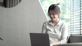 Attractive and happy young female Asian student studying online, sitting at desk, using laptop computer, having video chat, waving, education concept.