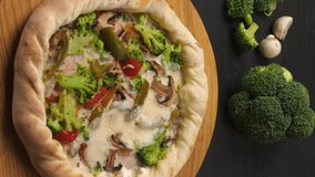 Vertical video. Presentation of pizza on a dark brown table with its ingredients.