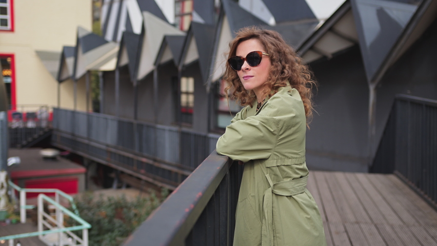 Young stylish woman in glasses and coat in art space