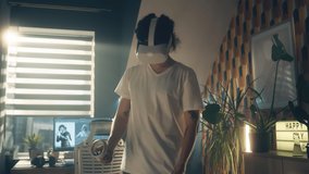 Man playing video game using VR headset and wireless controllers while spending leisure time at home. Virtual reality device. Cyberspace and metaverse