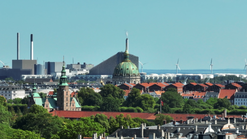Circular elevated footage of buildings surrounding Frederiks Kirke. Historic landmarks in city and industrial facilities on sea shore. Copenhagen, Denmark