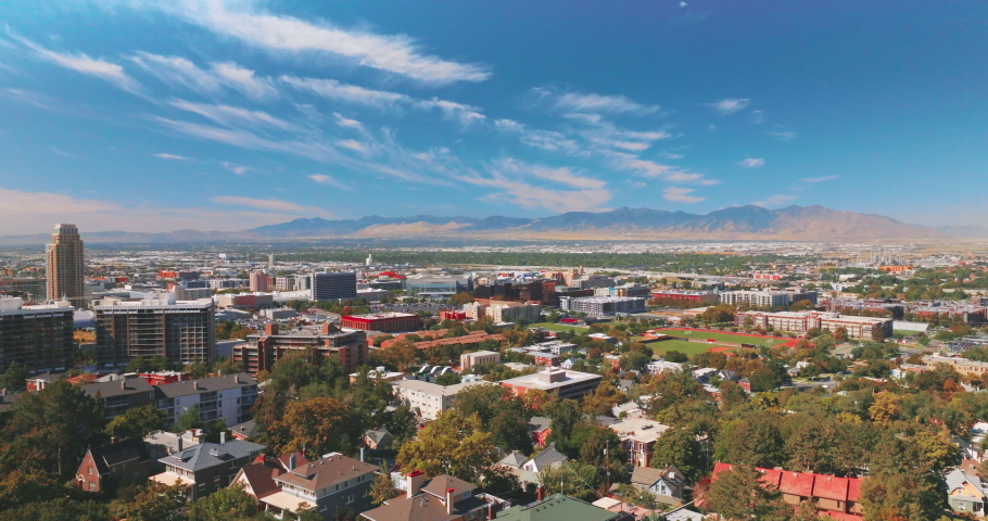 Medley panorama of amazing sunny Salt Lake City in Utah, USA. Vast city scenery with mountains at backdrop. Spindrift clouds in the sky over the urban landscape.