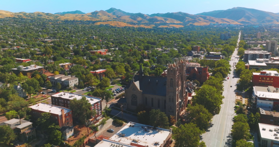Amazing green city with gorgeous cathedral. Sunny view of Salt Lake City, Utah, United States at backdrop of beautiful mountains.