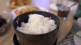 This video shows a spoon scooping rice from a black dish at a restaurant table.