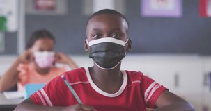 Animation of back to school text and school equipment over african american schoolboy in face mask. Childhood, school and education during coronavirus pandemic concept digitally generated video.