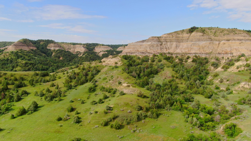 Scenic Prairie Hills And Rugged Badlands Buttes On A Sunny Day In North Dakota. aerial tilt-down