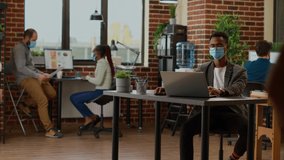 Project manager with face mask working with data on laptop, planning business presentation with charts and graphs. Creating company report with research information. Tripod shot. - Powered by Shutterstock - Get 15% off with code: PIKWIZARD15