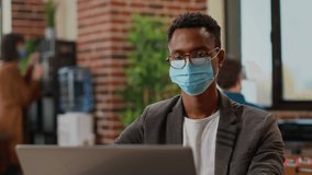 African american worker creating business report with research information on laptop, planning presentation and brainstorming ideas to work on analysis. Working in office with face mask. - Powered by Shutterstock - Get 15% off with code: PIKWIZARD15