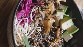 Vertical videos. Delicious poke bowl with buckwheat noodles, vegetables and sesame seeds on the table of vegan restaurant. Healthy lifestyle and natural organic food concept