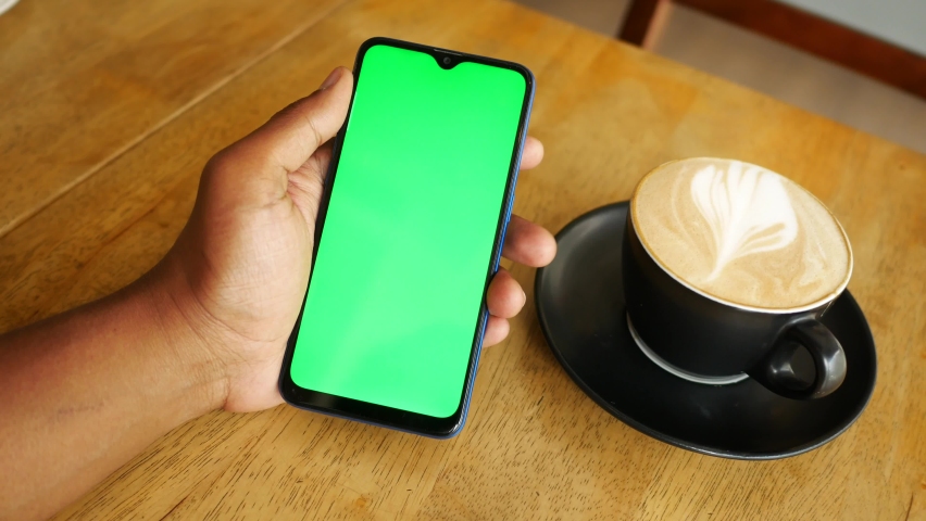 Holding a cpu of coffee and using smart phone with green screen  | Shutterstock HD Video #1094645055