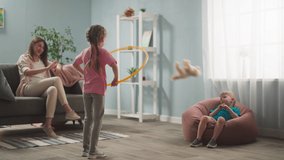 young woman, mother with children playing in room, throwing toys, twisting hoop, weekend with children, family - Powered by Shutterstock - Get 15% off with code: PIKWIZARD15